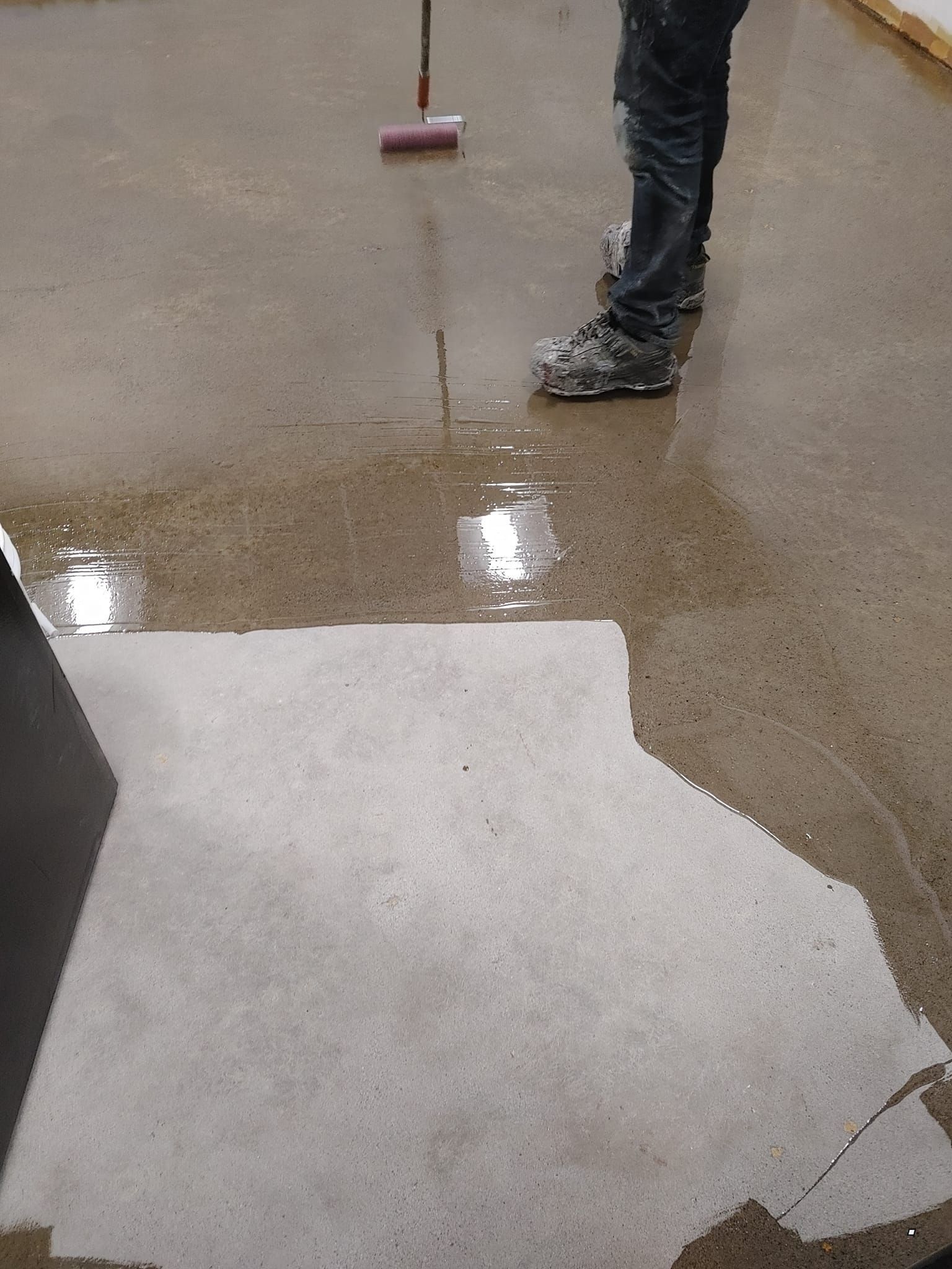 Une personne se tient debout sur un sol mouillé avec un balai.