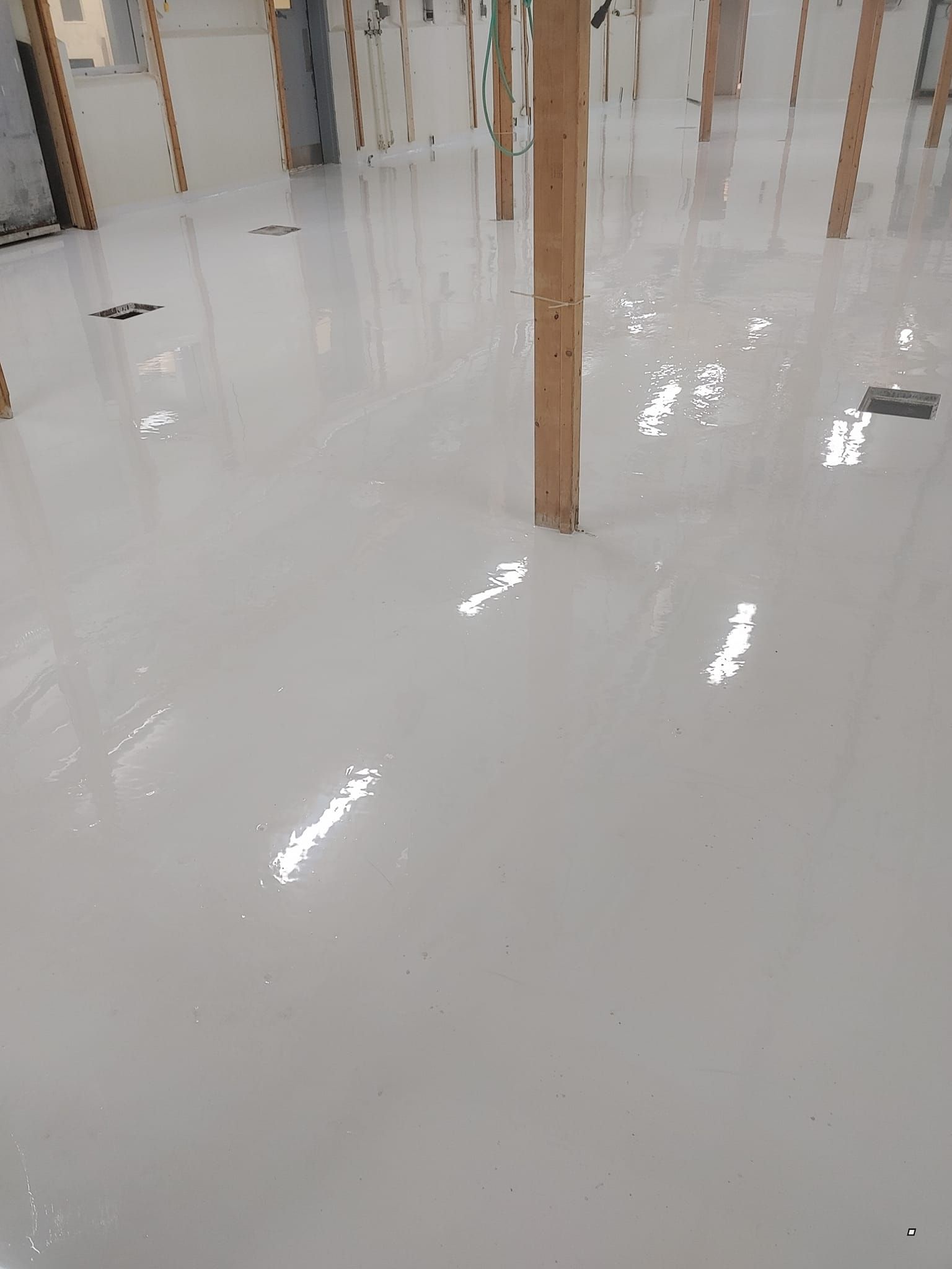 Une grande pièce avec un sol blanc et des piliers en bois.