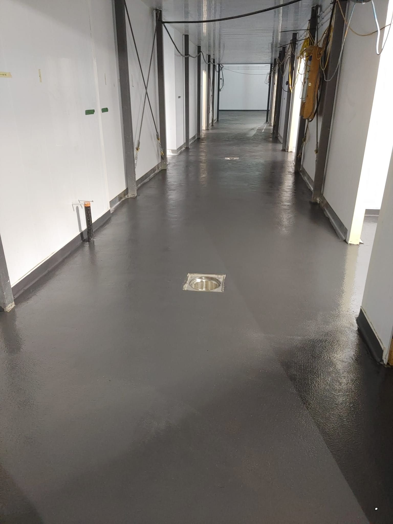 Un long couloir avec un drain au milieu.