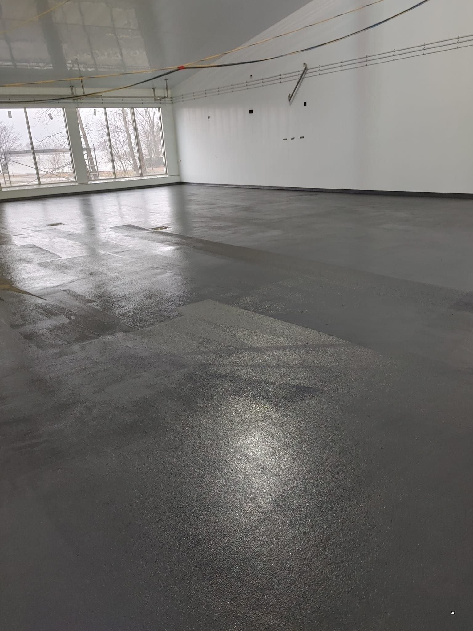 Une grande pièce avec un sol gris et des murs blancs