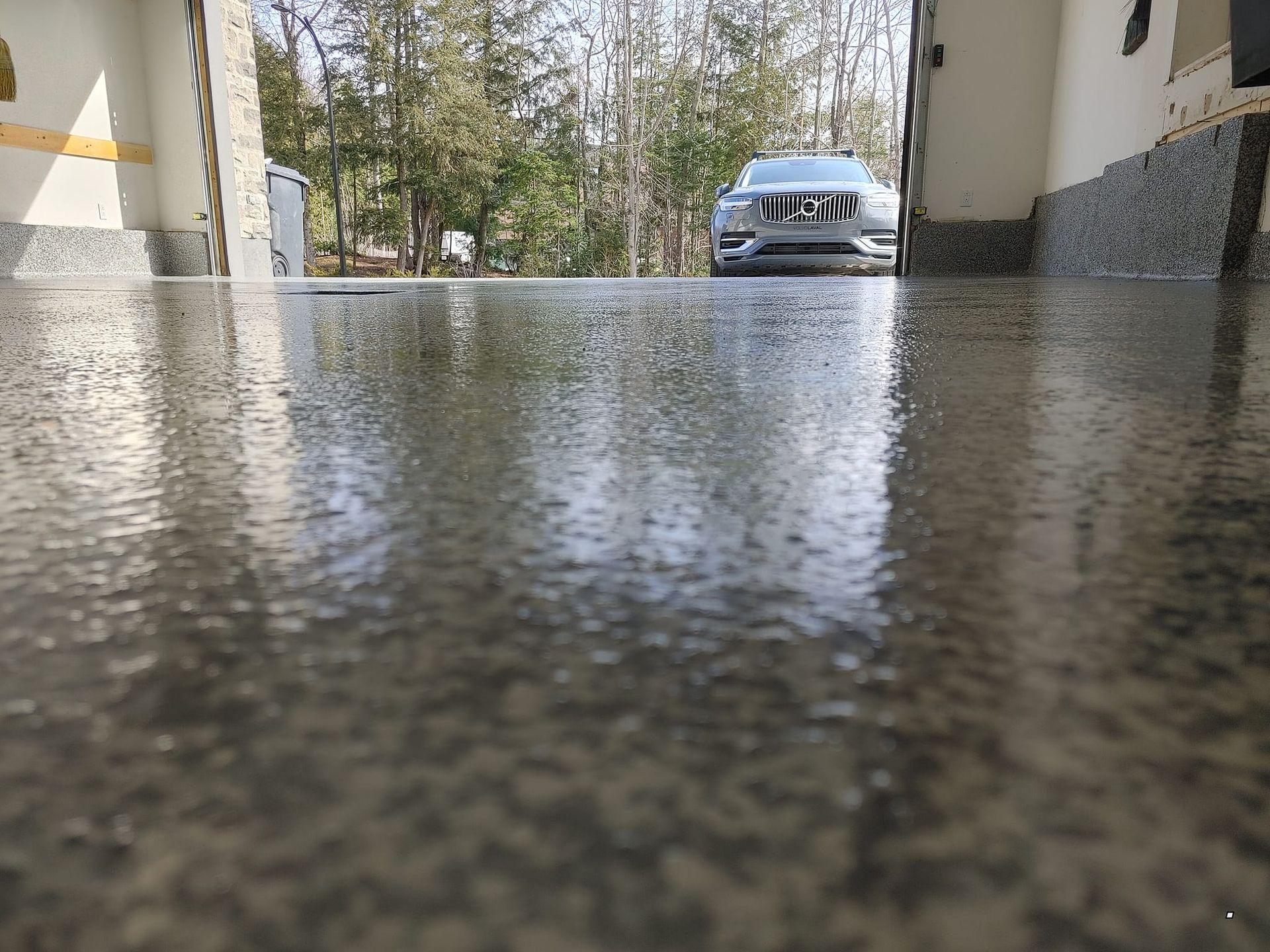 Une voiture est garée dans un garage avec un sol en béton brillant.