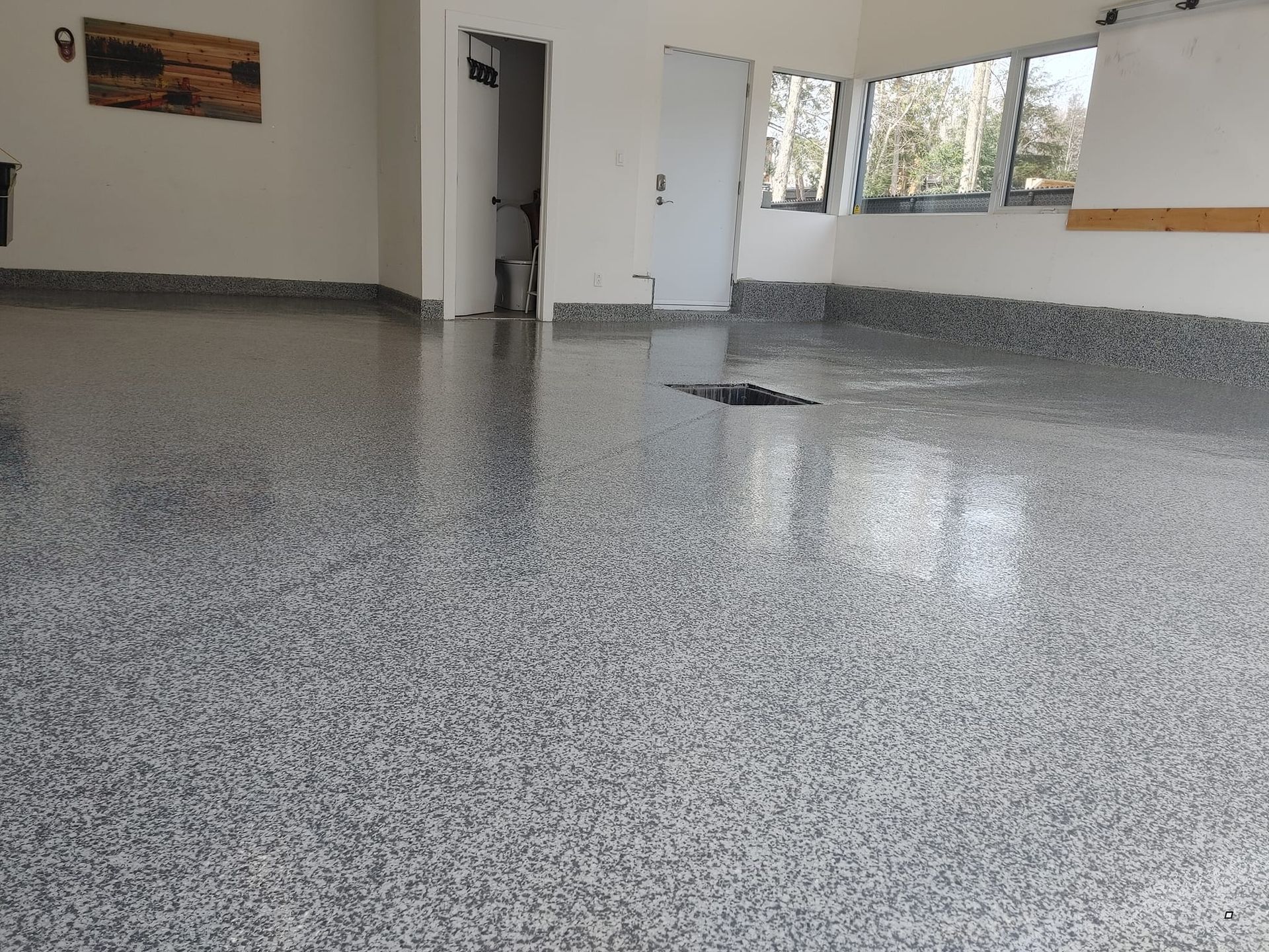 Une grande pièce avec un sol gris et des murs blancs