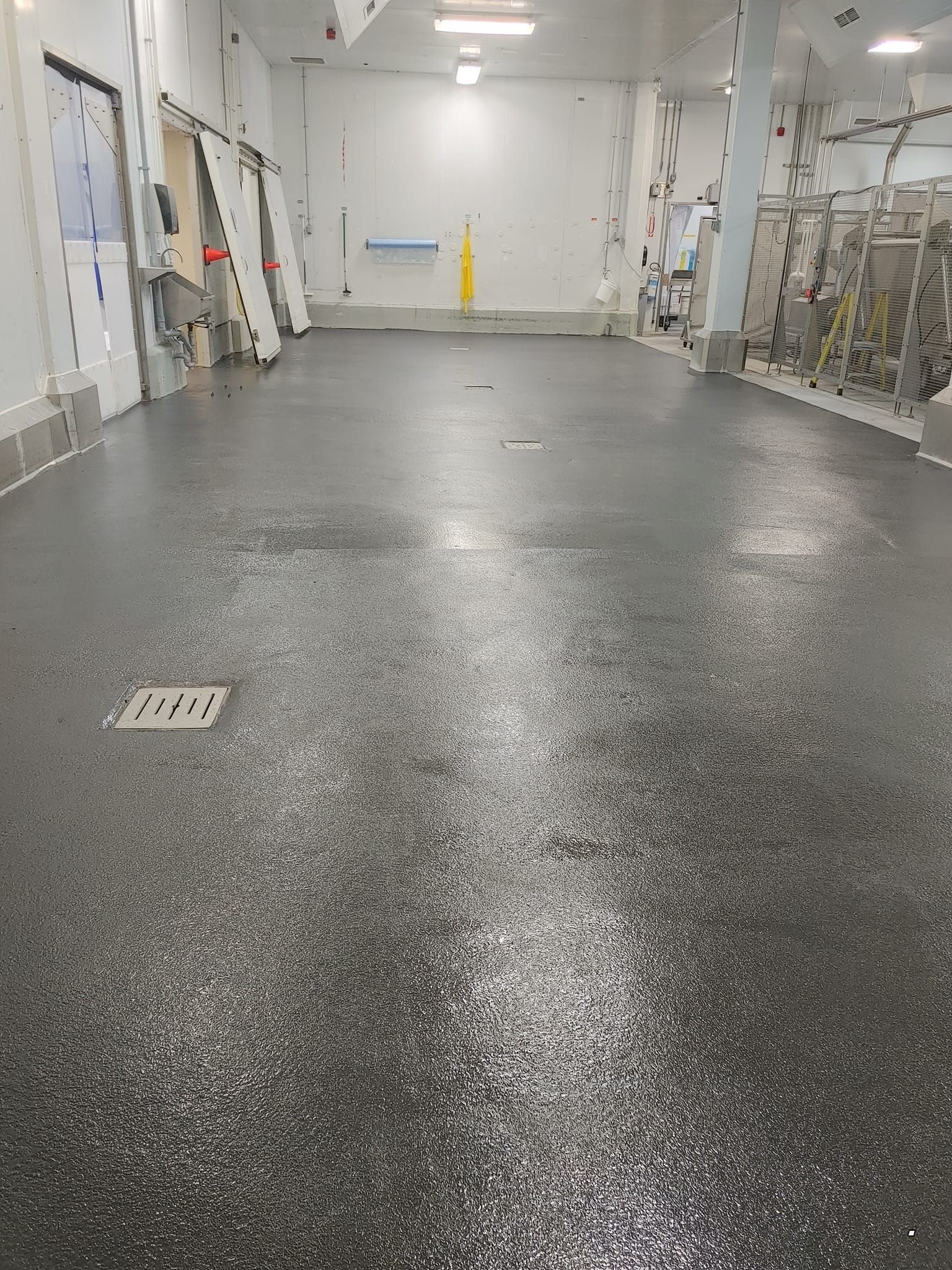 Un grand entrepôt avec un sol noir et des murs blancs.