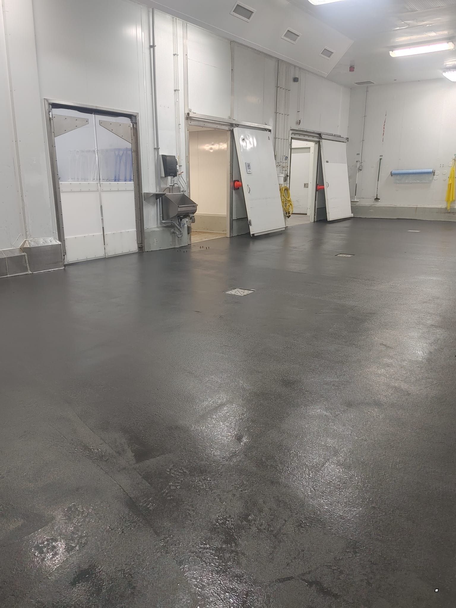 Une grande pièce avec un sol noir et des murs blancs.