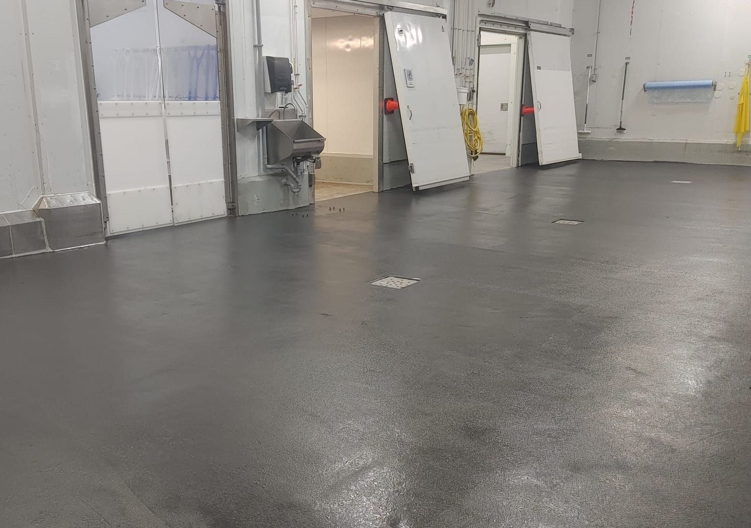 Une grande pièce avec un sol en béton et des portes coulissantes.