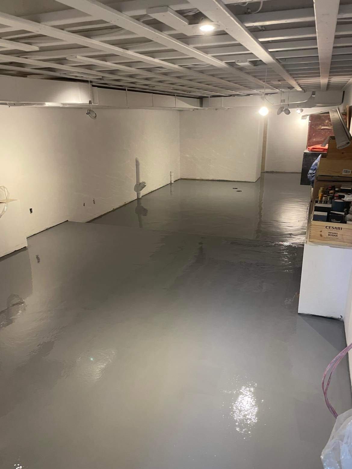 Une grande pièce vide avec un sol gris et des murs blancs.