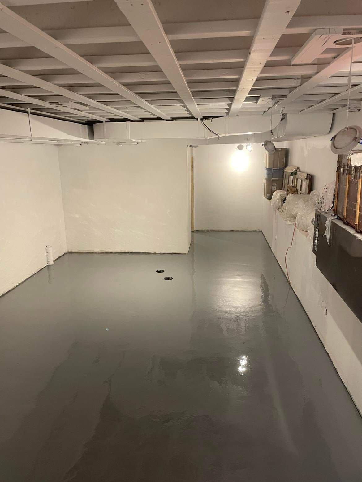 Un sous-sol avec un sol gris et des murs blancs.