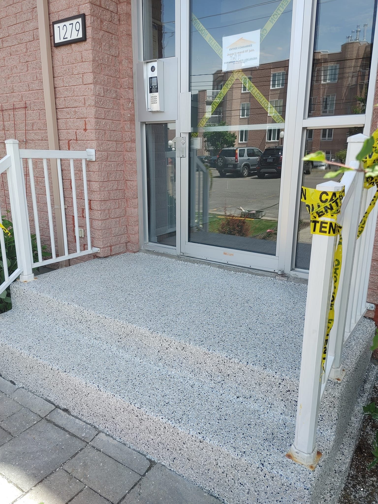 Une porte avec une balustrade blanche et un ruban d'avertissement jaune.