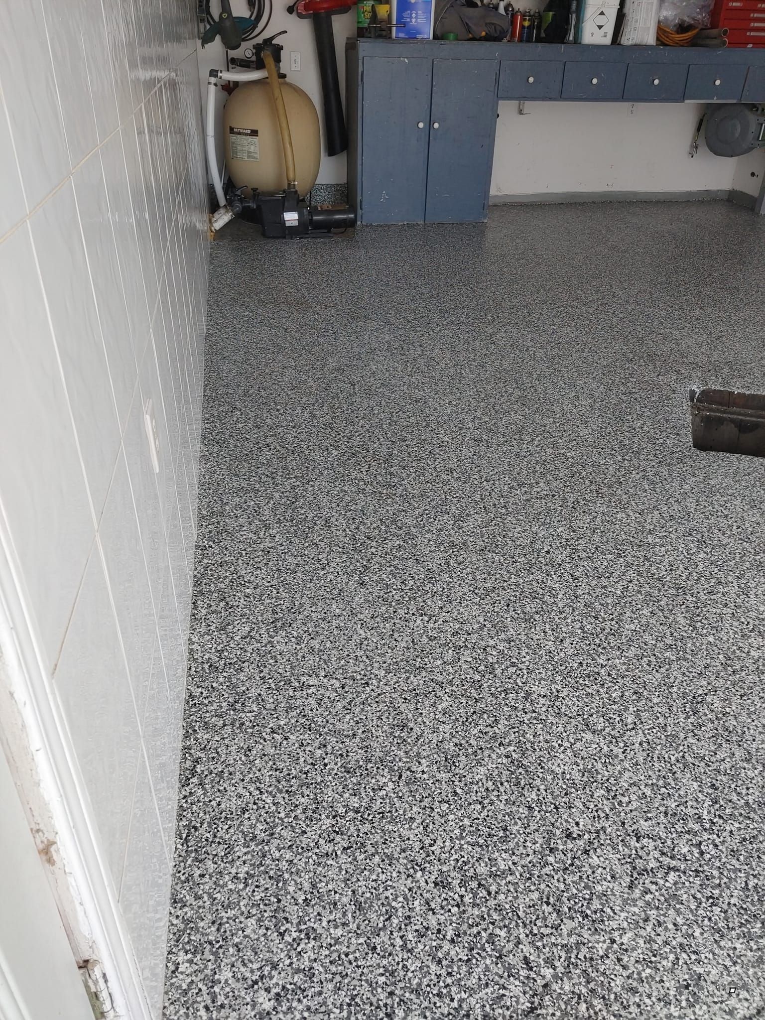 Un garage avec un sol gris et un mur blanc.