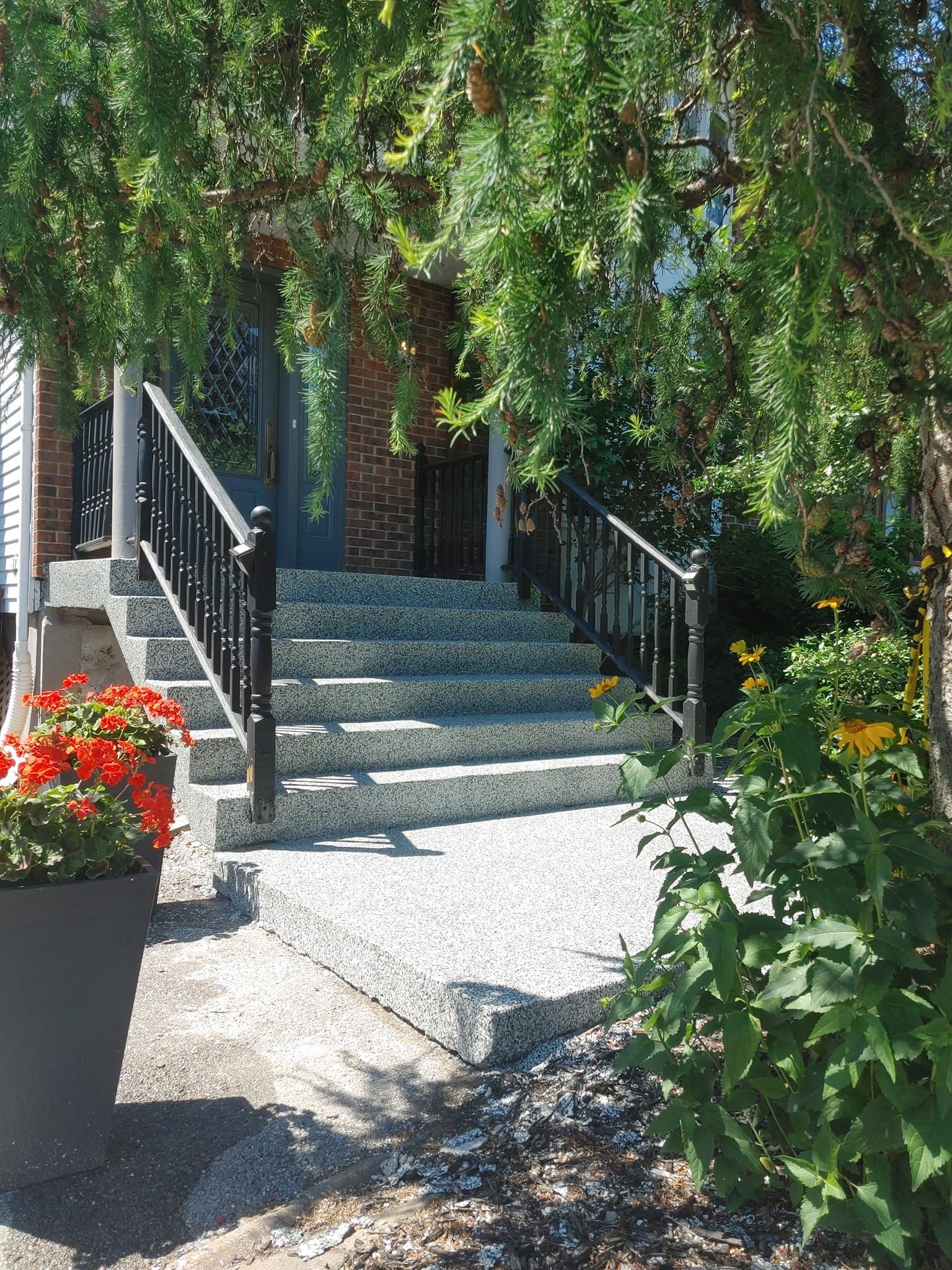 Un ensemble d'escaliers menant à une maison entourée d'arbres et de fleurs.