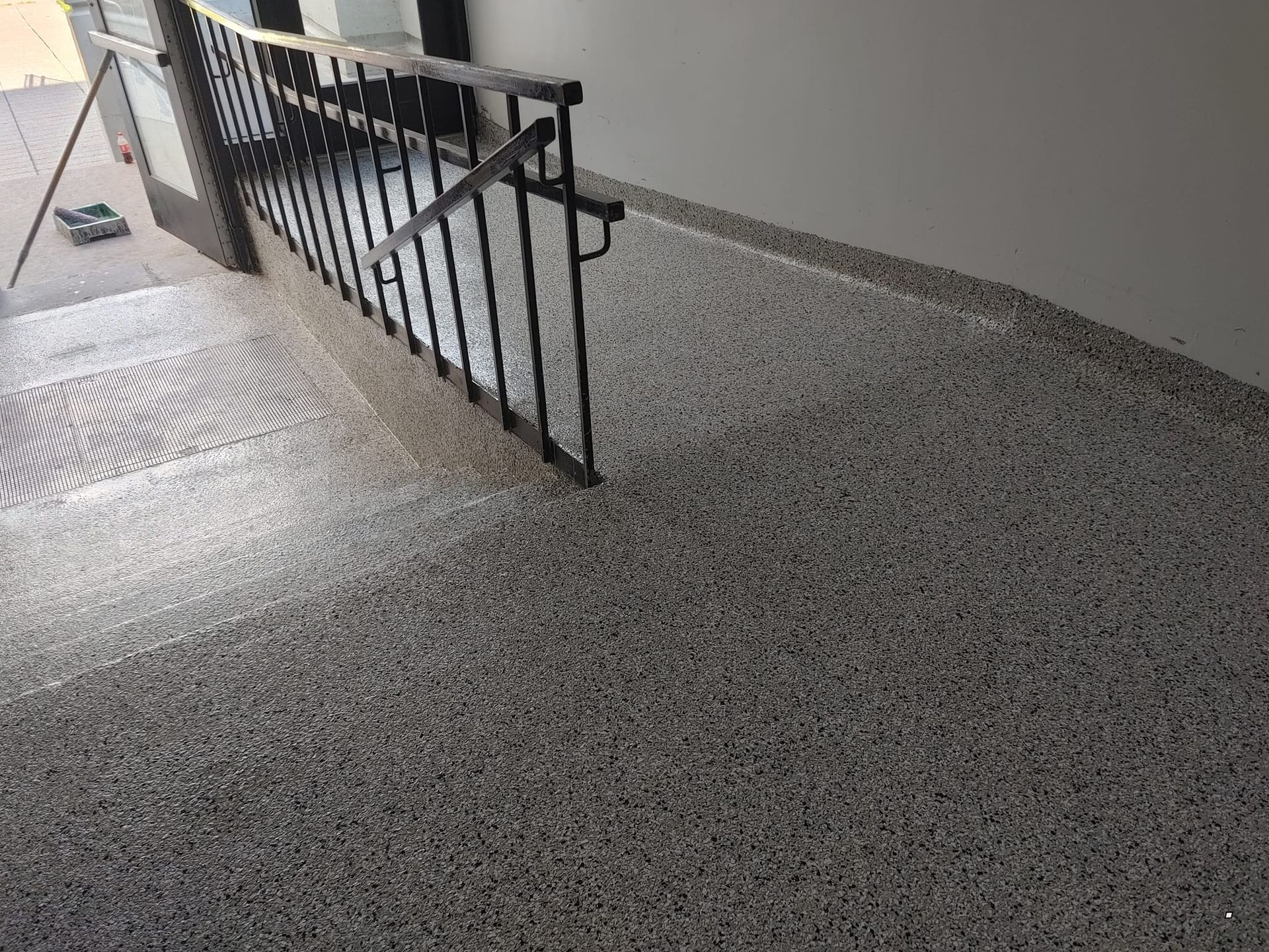 Un escalier avec une rampe en métal et un sol en béton.