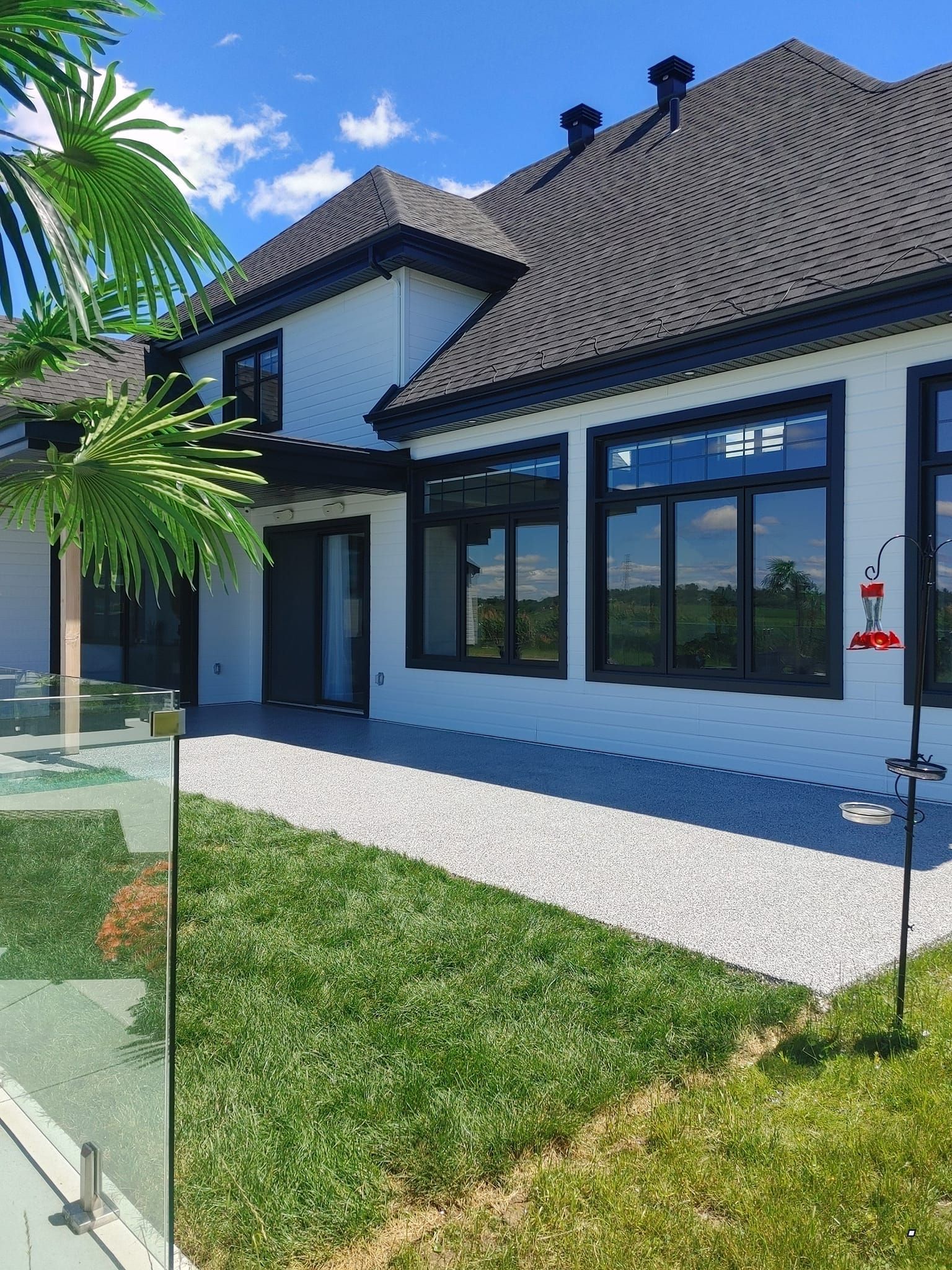 Une grande maison blanche avec un toit noir et beaucoup de fenêtres.