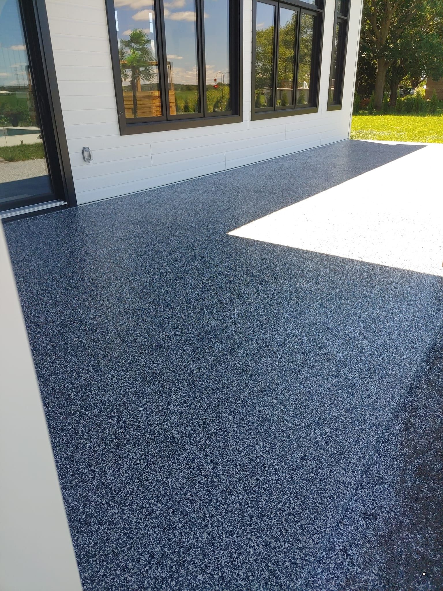 Un sol en béton noir avec un bâtiment blanc en arrière-plan.