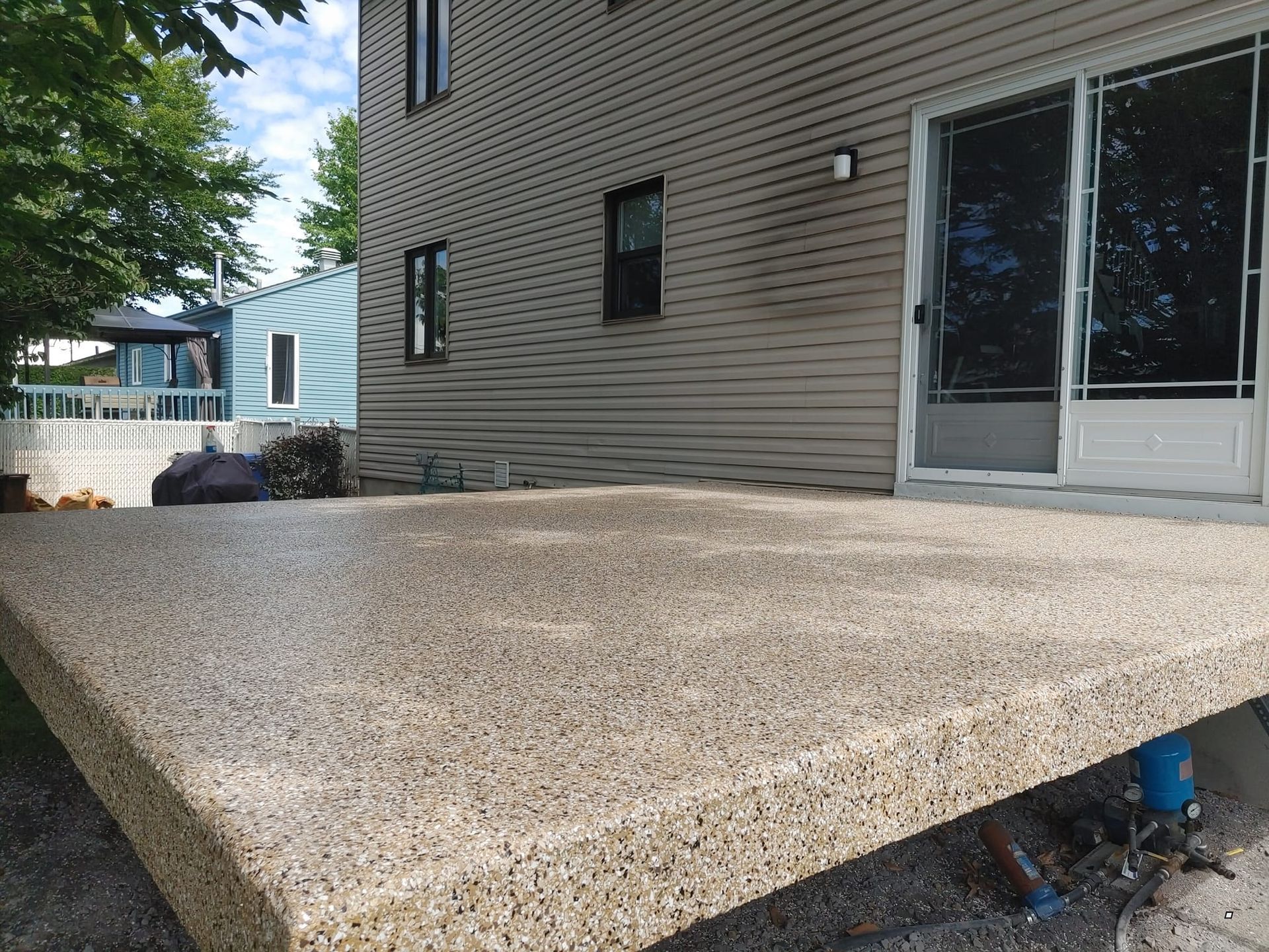 Une terrasse en béton devant une maison avec une porte coulissante en verre