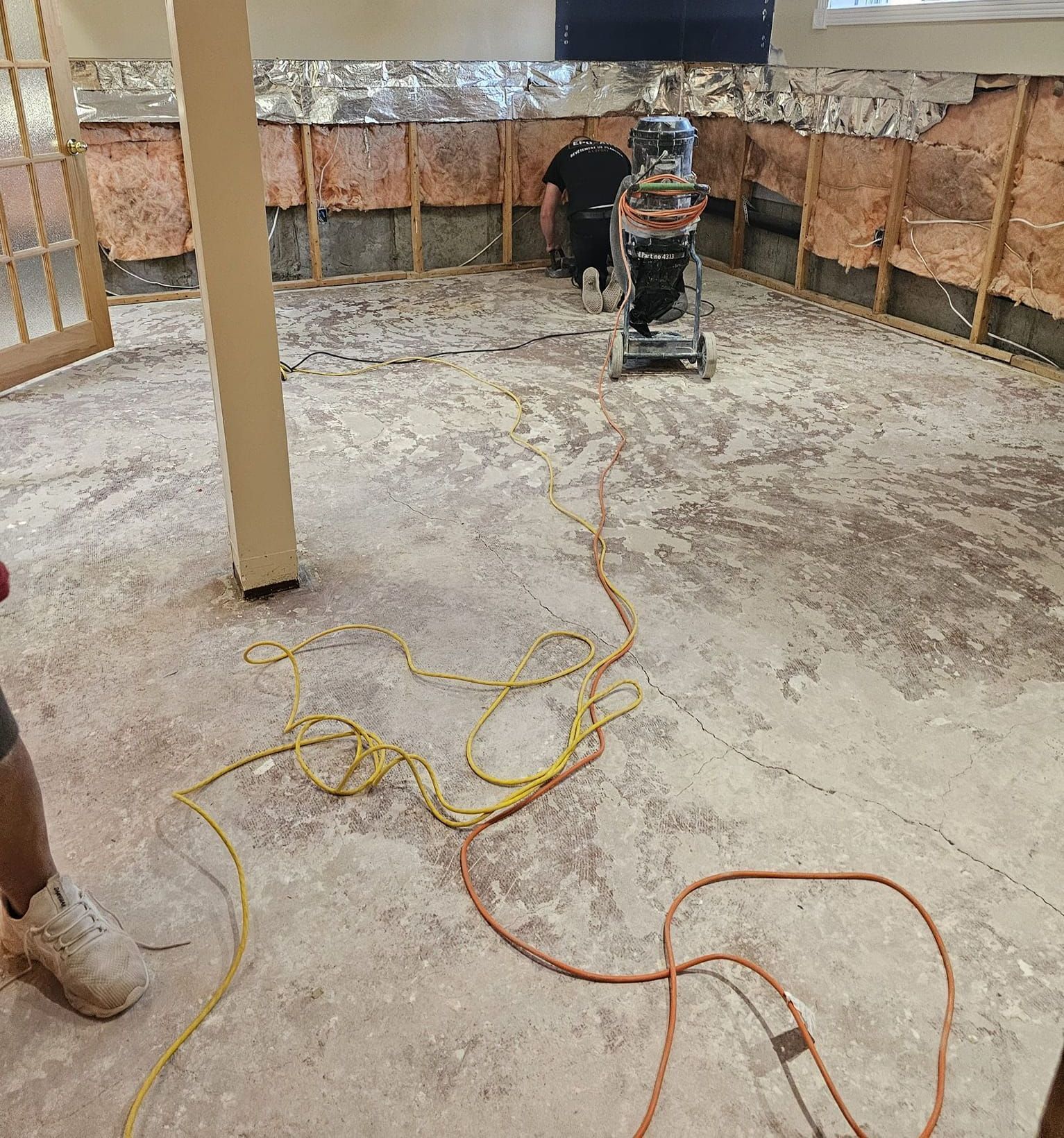 Un homme utilise un aspirateur pour nettoyer le sol d'un sous-sol.