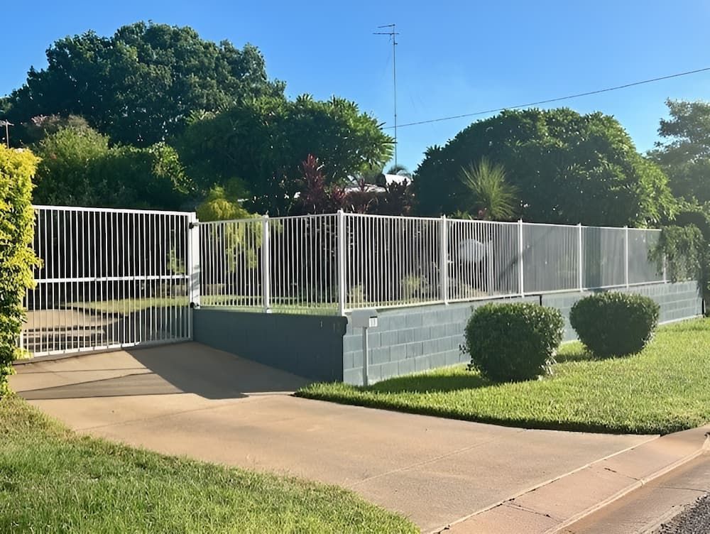 A White Fence Surrounds A Driveway With Trees — PH Davie in Mount Isa, QLD