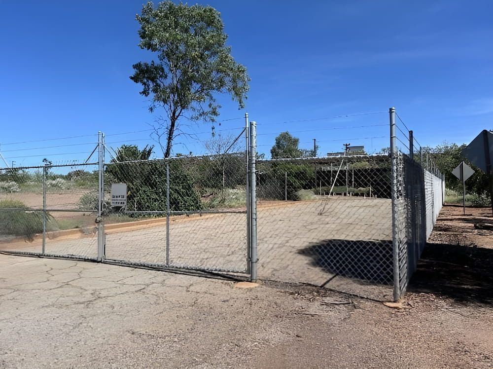 A Chain Link Fence With A Tree In The Background — PH Davie in Mount Isa, QLD
