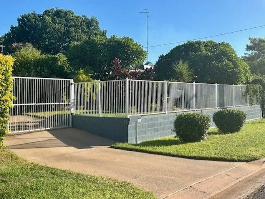 A White Fence Surrounds A Driveway With Trees — PH Davie in Mount Isa, QLD