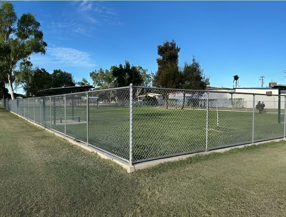 A Chain Link Fence Surrounds A Lush Green Field — PH Davie in Mount Isa, QLD
