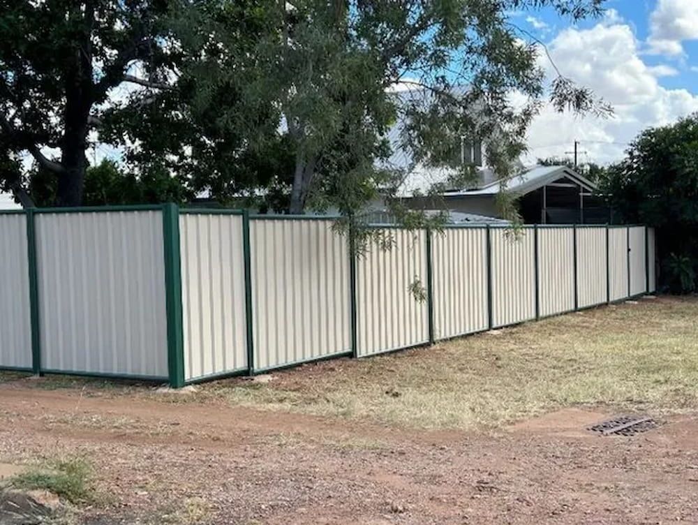 A White And Green Fence Surrounds A Dirt Field — PH Davie in Mount Isa, QLD