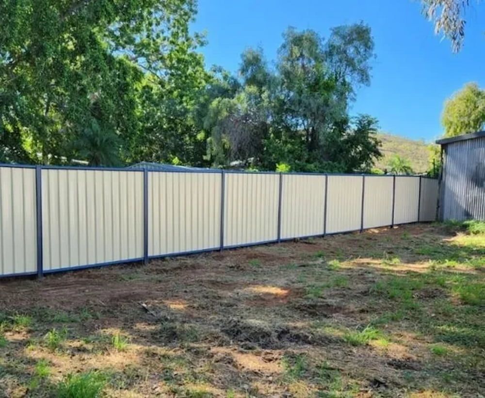 A White Fence Surrounds A Dirt Field With Trees — PH Davie in Karumba, QLD