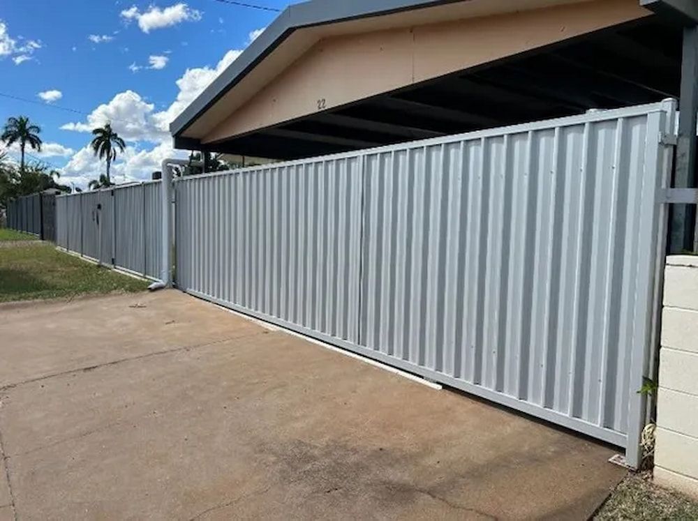 A White Fence Surrounds A Driveway In Front Of A House — PH Davie in Mount Isa, QLD