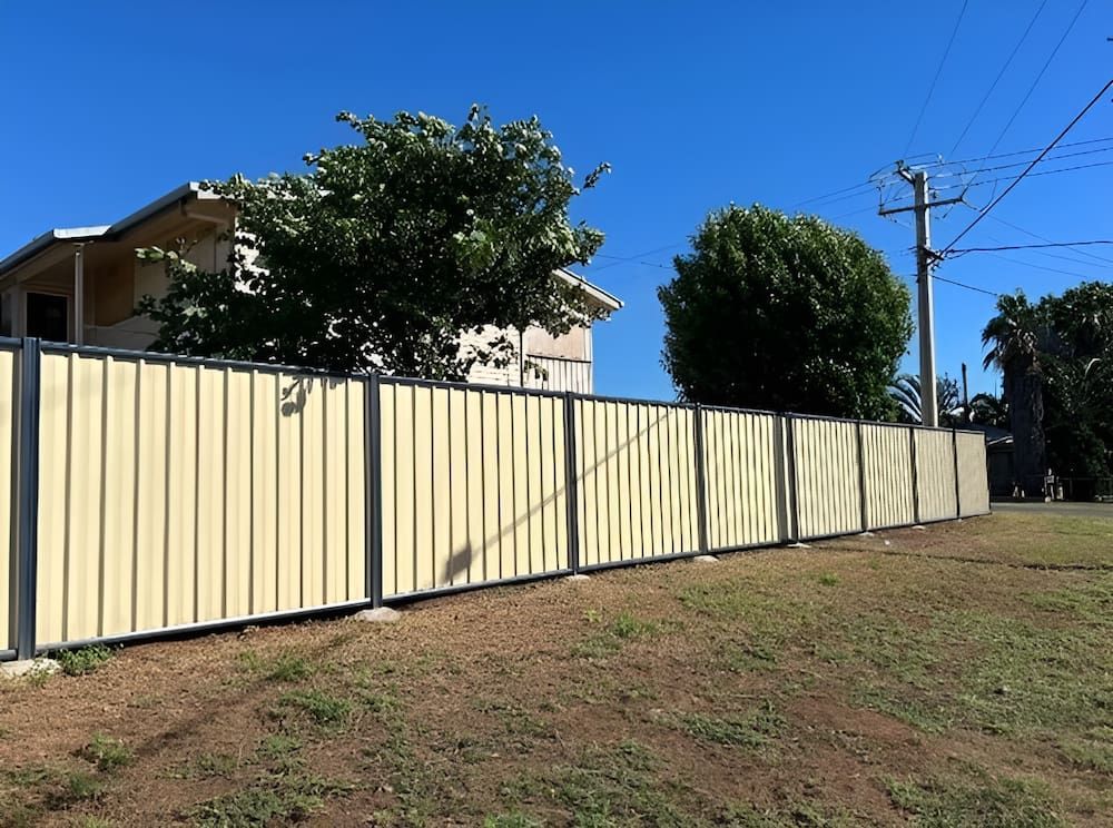 A Yellow Fence Surrounds A Grassy Field In Front Of A House — PH Davie in Mount Isa, QLD