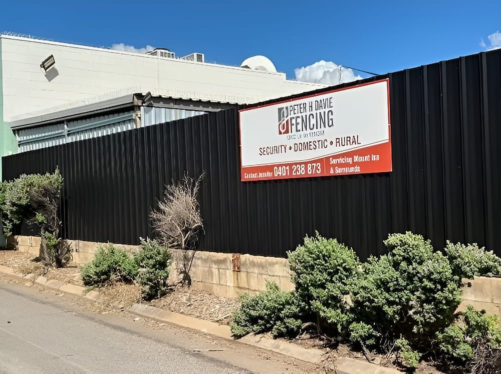 A Black Fence With A Sign On It That Says Baptist & White Fencing — PH Davie in Mount Isa, QLD