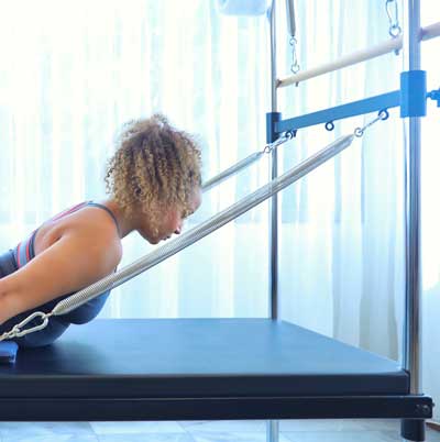 A woman is doing exercises on a pilates machine.