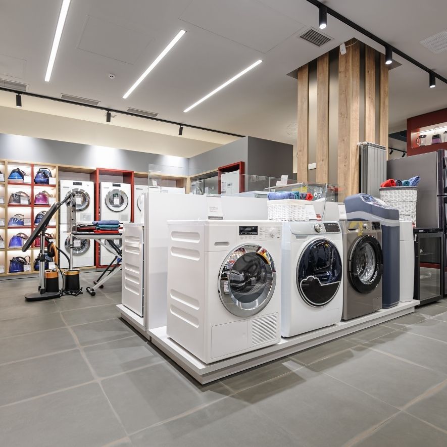 Machines à laver et sèche-linge exposés dans un magasin d'électroménager lumineux.