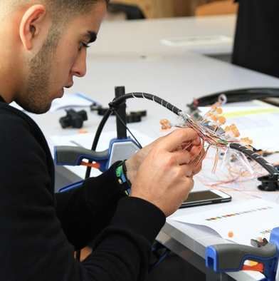 Photo d'un alternant en cours de pratique en train de manipuler des cables