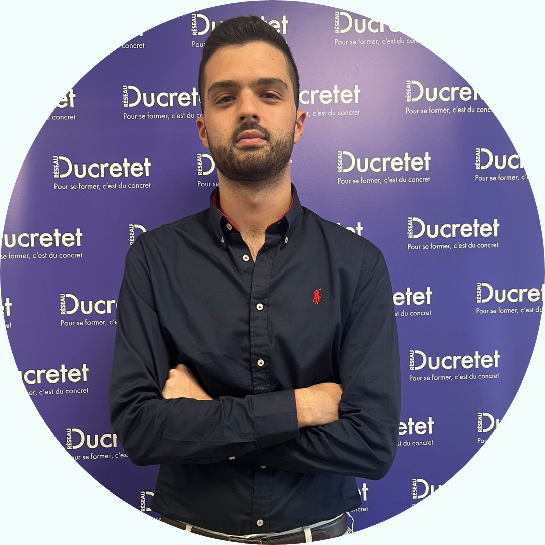 Homme aux bras croisés devant un fond sur lequel est répété le mot « Ducretet ».