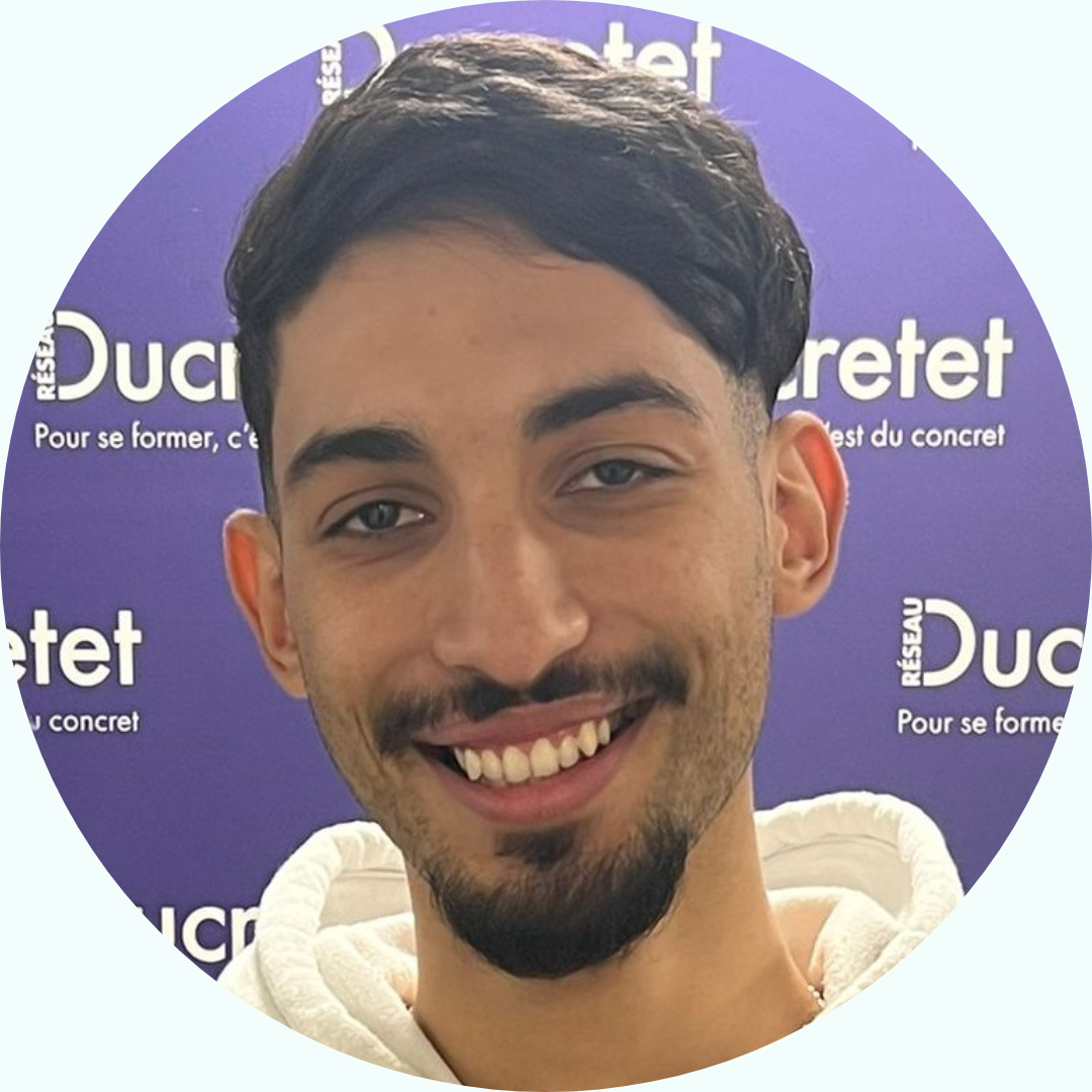 Homme souriant aux cheveux noirs et à la barbe, devant un fond violet avec du texte.