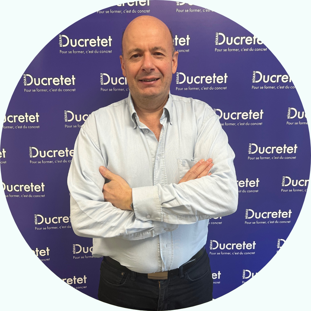 Homme aux bras croisés devant le décor Ducretet.