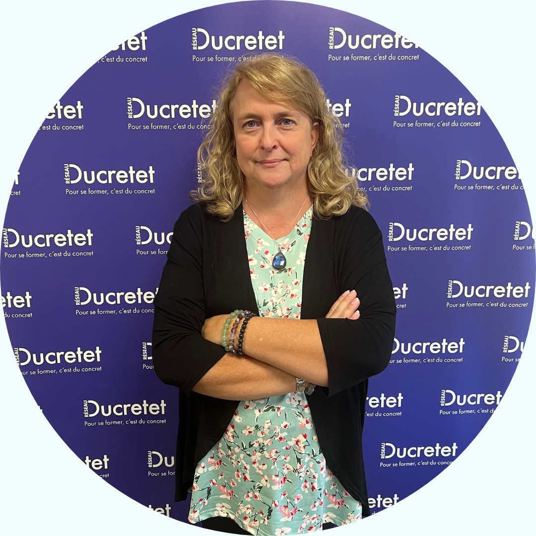 Femme aux bras croisés devant un fond sur lequel est répété le mot « Ducretet ».