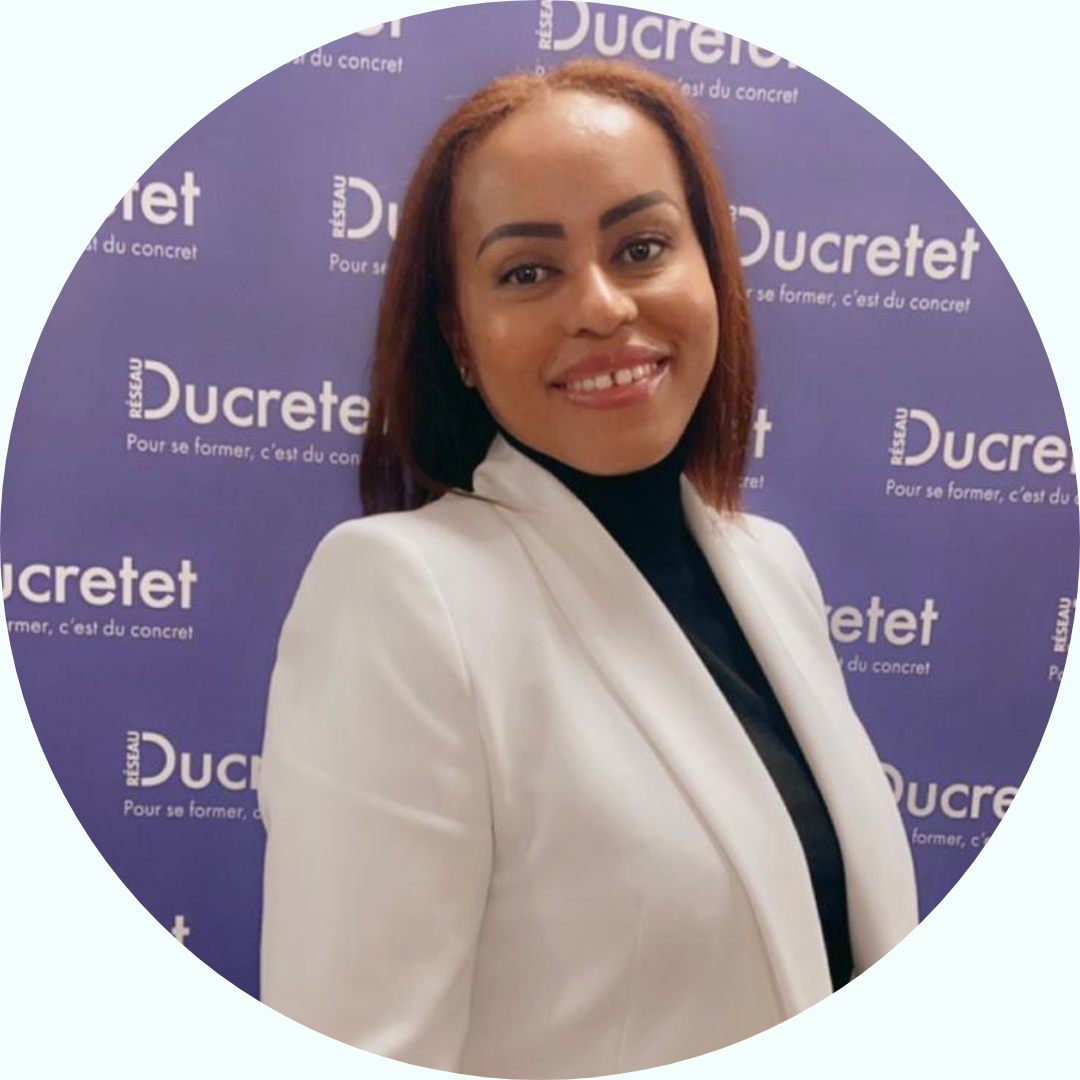 Une femme en blazer blanc et col roulé noir sourit devant un fond violet avec le texte « Ducretet ».