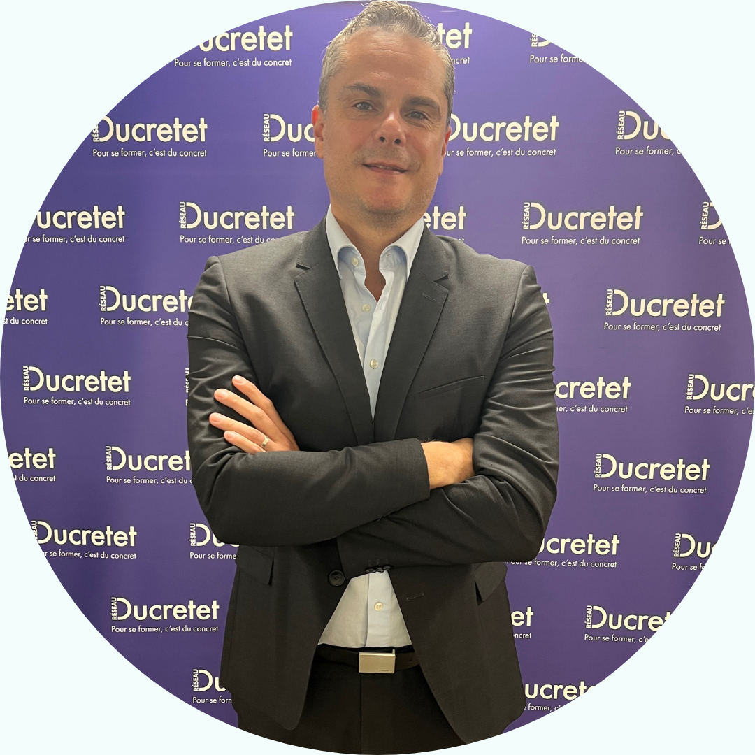 Homme en costume, bras croisés, debout devant un décor 