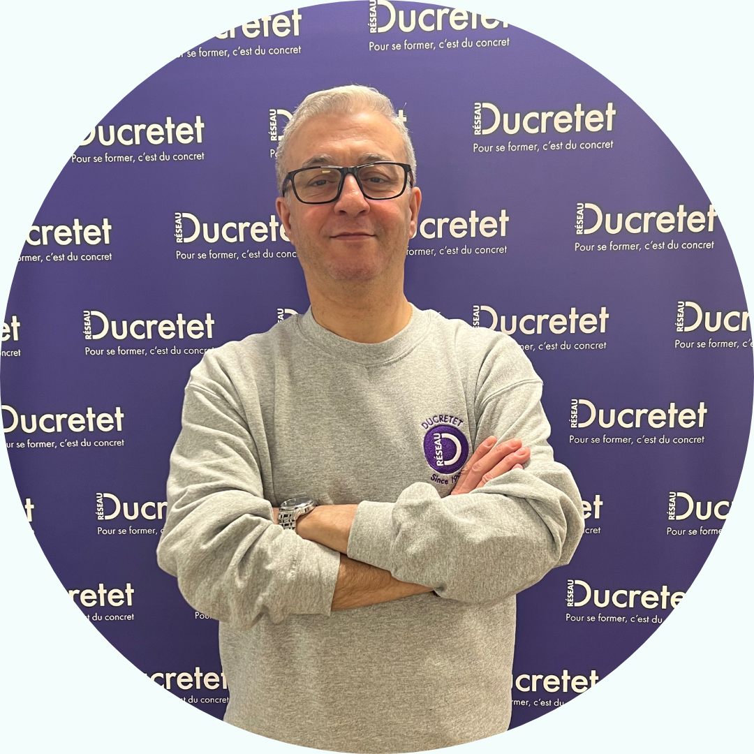 Homme en sweat-shirt gris, les bras croisés, devant un fond avec le mot 