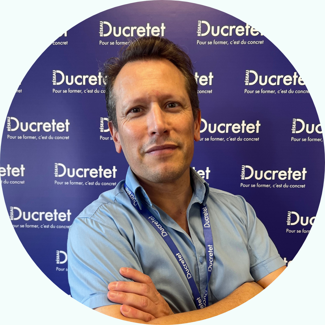 Homme aux bras croisés devant un fond bleu Ducretet.