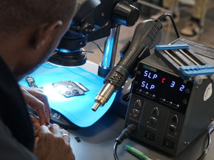 Homme en train de réparer un téléphone durant la formation courte Ducretet