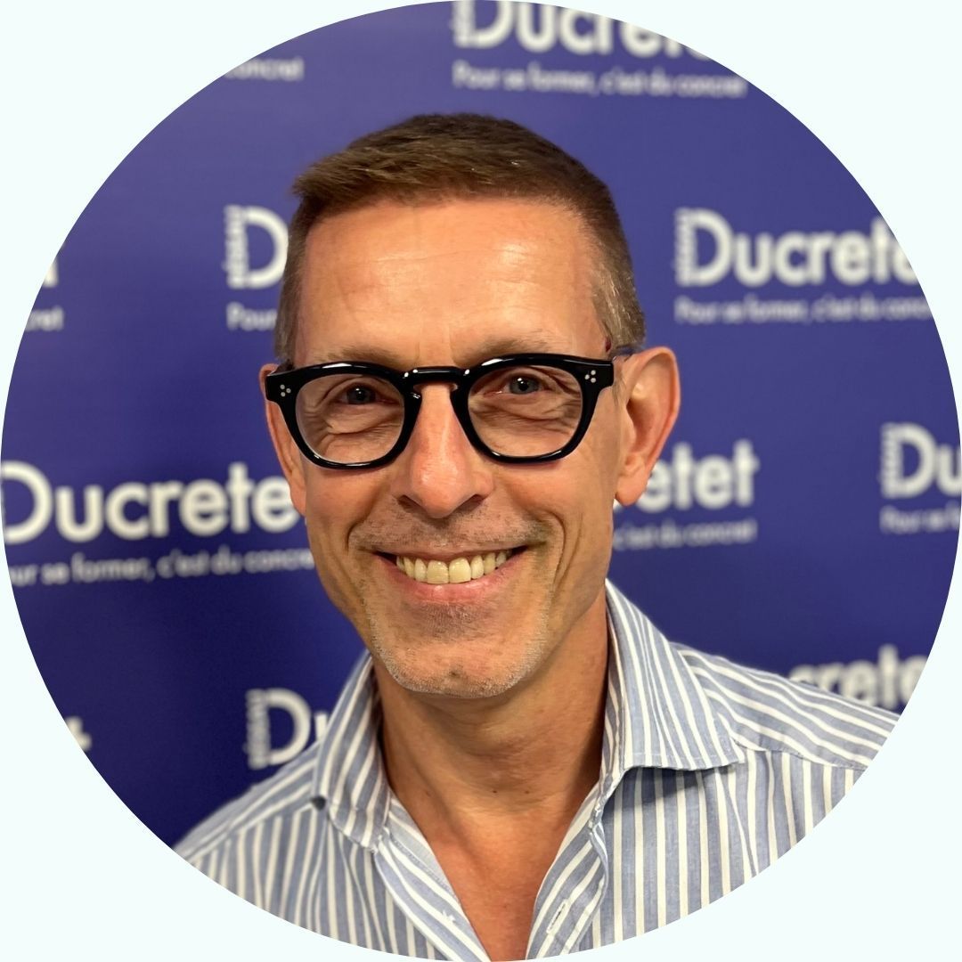 Homme à lunettes souriant, devant un fond bleu 