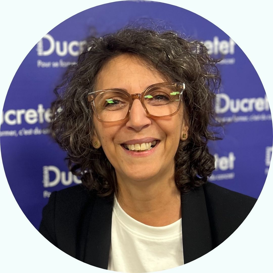 Femme souriante avec des lunettes devant un fond bleu Ducretet.