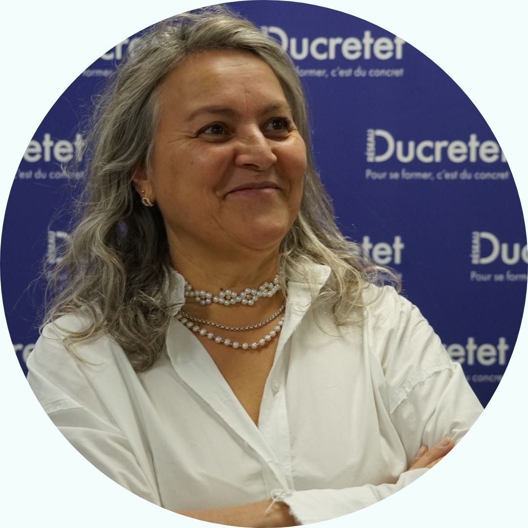 Femme aux cheveux grisonnants portant une chemise blanche, regardant sur le côté, avec un fond 