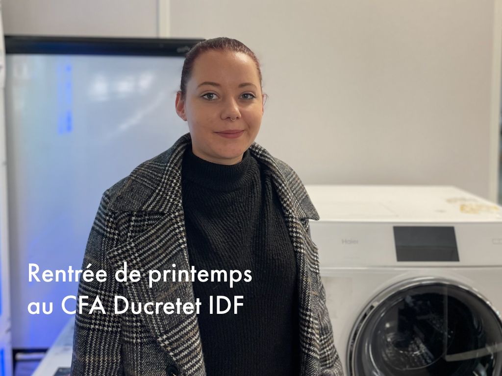 Une femme se tient devant une machine à laver.
