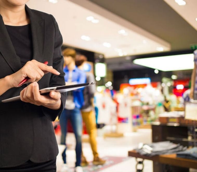 Une personne en blazer noir désigne une tablette dans un magasin.