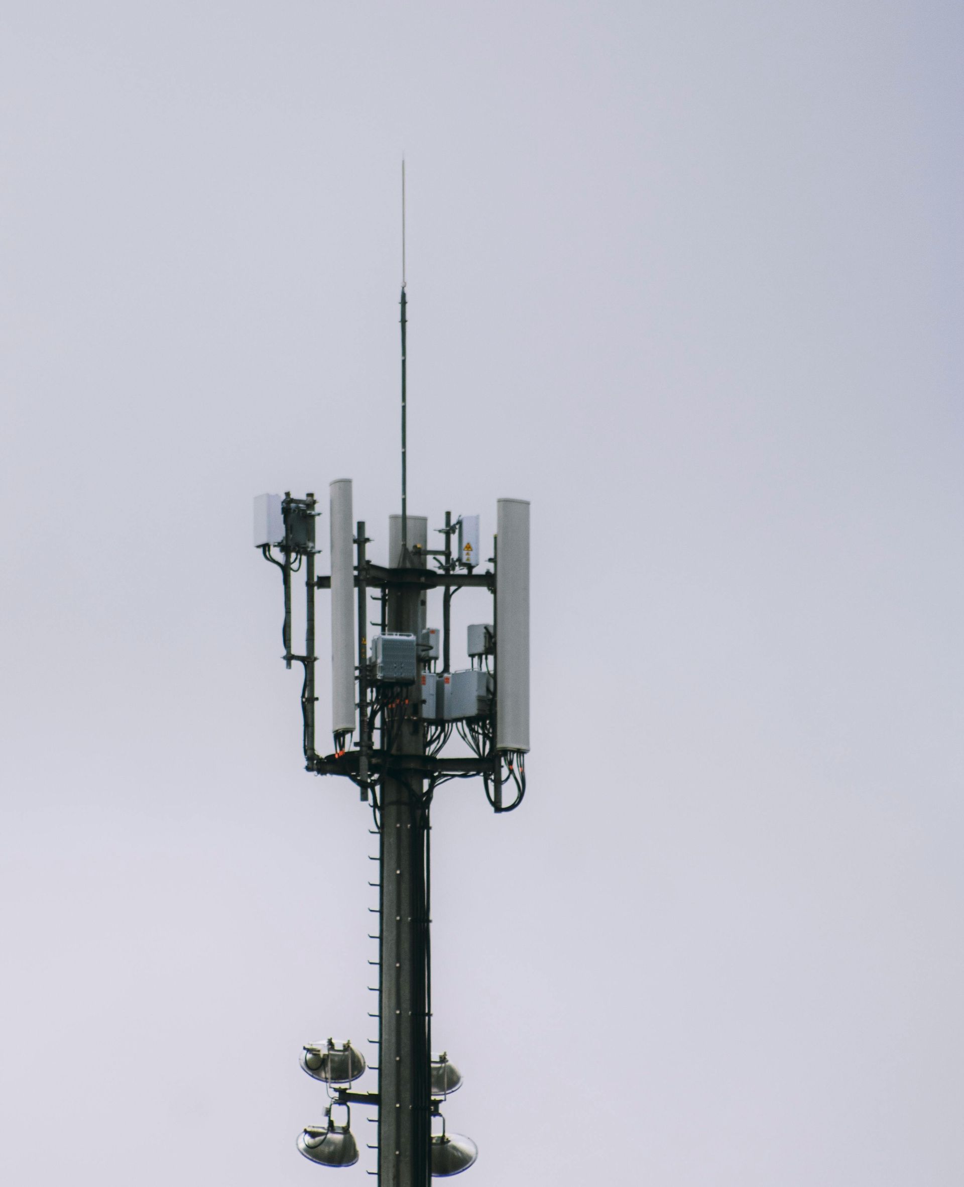 Antenne-relais de téléphonie mobile se détachant sur un ciel gris et nuageux. L'antenne est équipée de divers dispositifs.