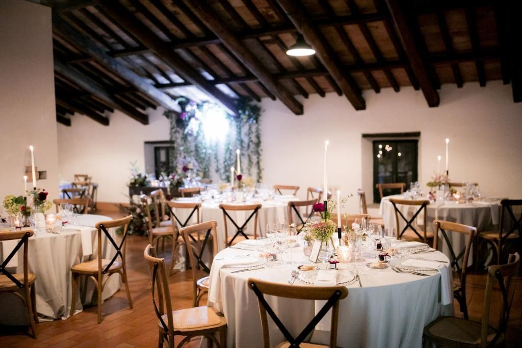 Un'ampia sala con tavoli e sedie allestita per un ricevimento di nozze.