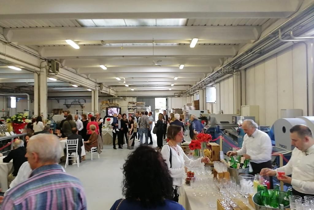 Un gruppo di persone è in piedi attorno a un bar in una grande stanza.