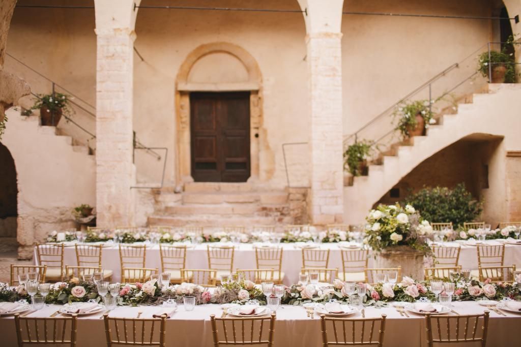 Un lungo tavolo con fiori sopra davanti a un edificio con scale.