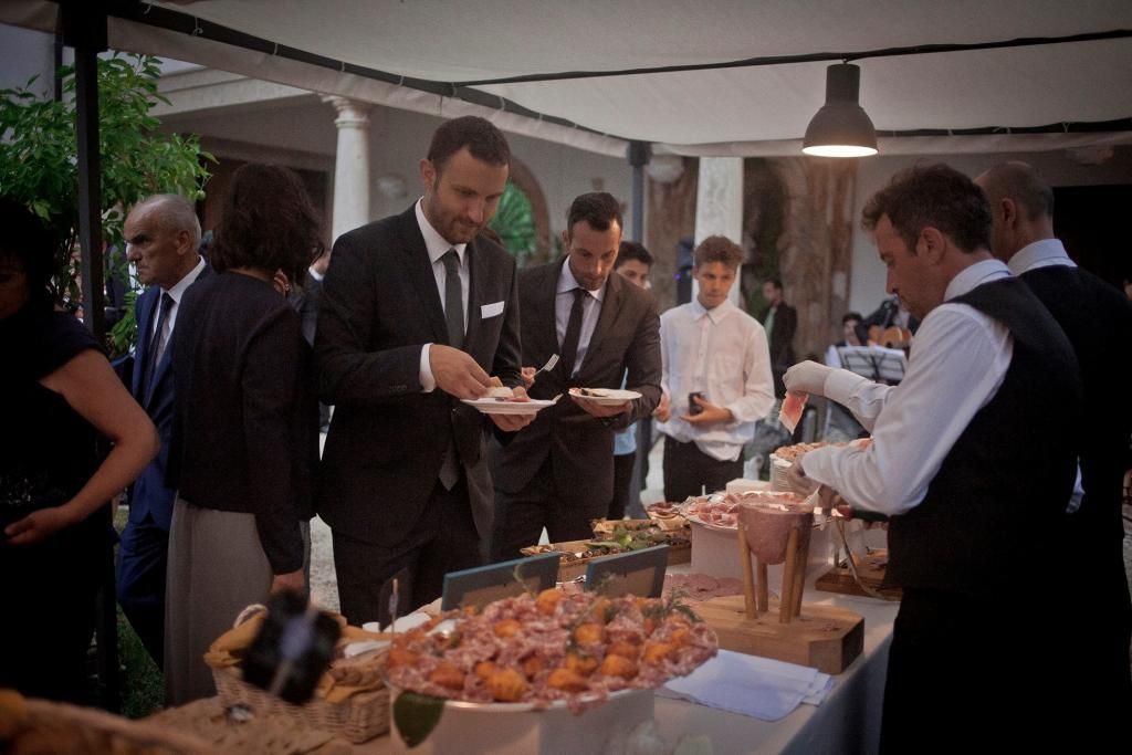 Un gruppo di persone è in piedi attorno a un tavolo ad un ricevumento organizzato da Sciamannini Ricevumenti